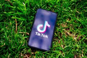 Handy auf grüner Wiese mit TikTok Logo auf dem Bildschirm